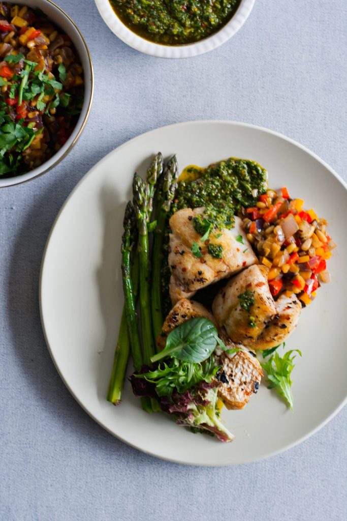 Snapper, green salsa, caponata, asparagus on white plate