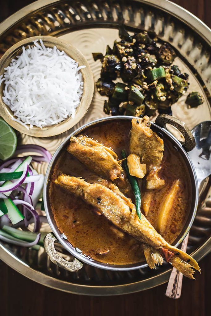 Indian fish curry along with rice and veggies served on platter