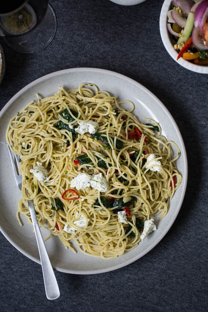 Spaghetti with spinach and goat's cheese on grey plate