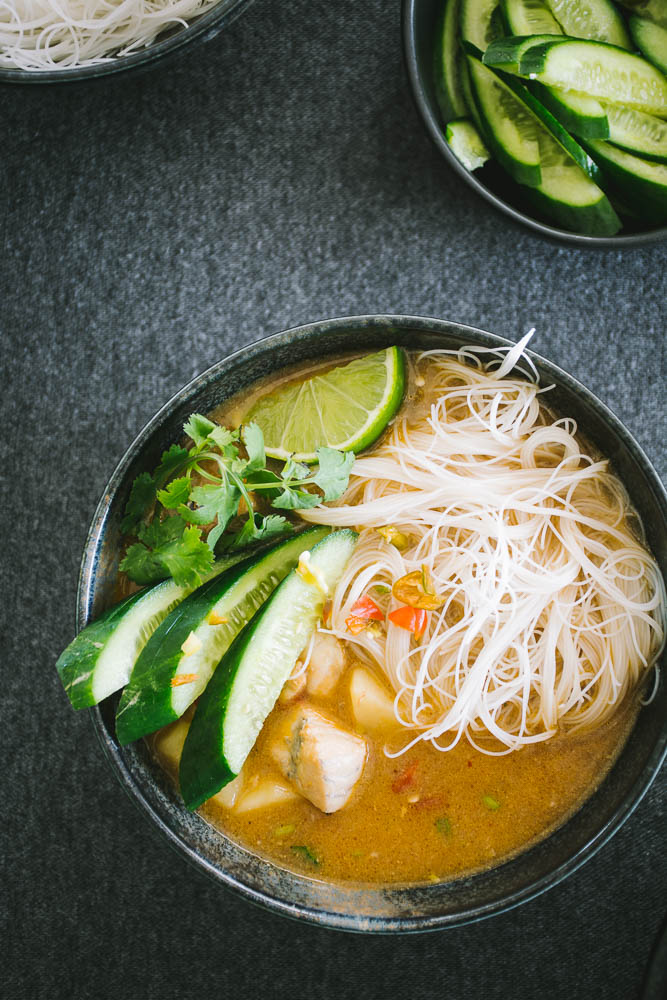 Indonesian style fish stew with noodles in black bowl