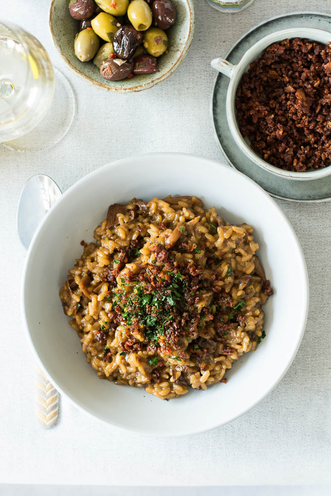 Mushroom risotto in bowl with olives on the side