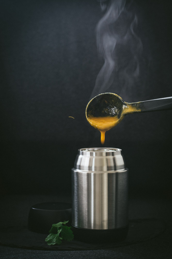 Pouring steaming hot carrot soup into thermos