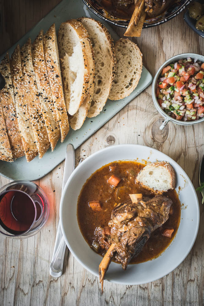 Slow cooked lamb shanks with curry powder and sliced bread on the side