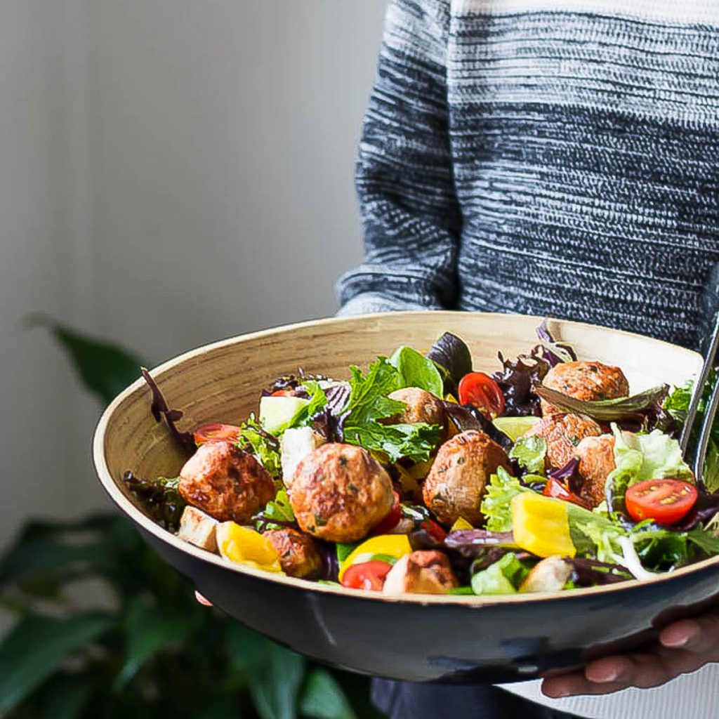 boy holding chicken meatball salad in a large bowl