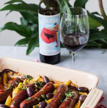 Sausage and potato bake in tray with red wine on the side