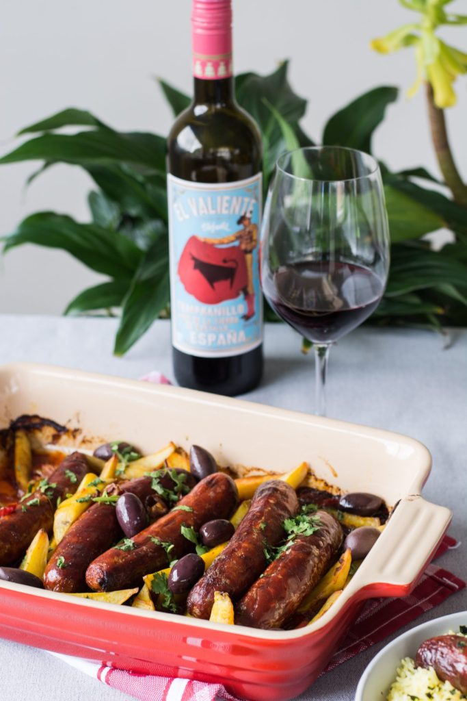 Sausage and potato bake in tray with red wine on the side