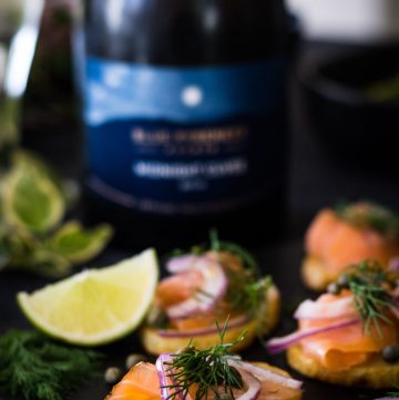 Close up of Potatoes topped with smoked salmon, capers, dill with wine bottle in background