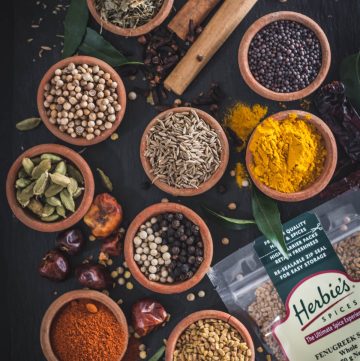 an array of whole spices in small earthenware bowls