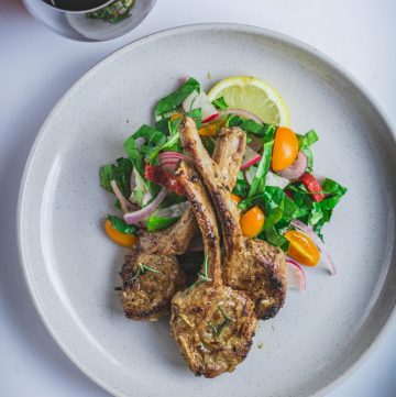 Roasted lamb chops with salad on grey plate