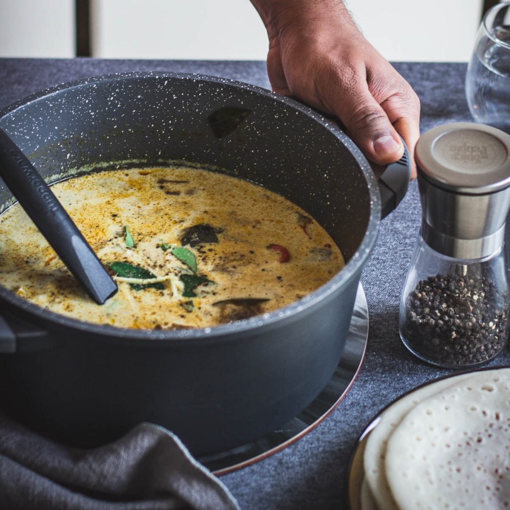 hand holding a pot with chicken stew