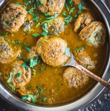 Egg Paniyaram Curry in silver bowl with spoon