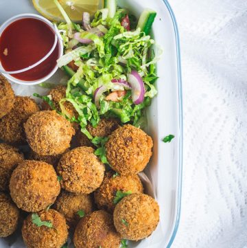 Indian beef croquettes with salad and sauce on the side in white platter