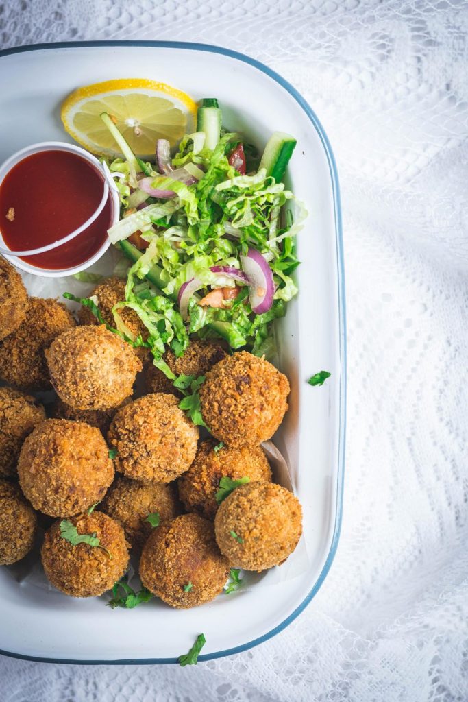 Indian beef croquettes with salad and sauce on the side in white platter