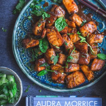 tamarind crispy skin salmon on blue plate with cookbook on the side