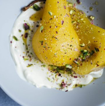 Poached Pears served with creme fraiche and pistachios in blue bowl
