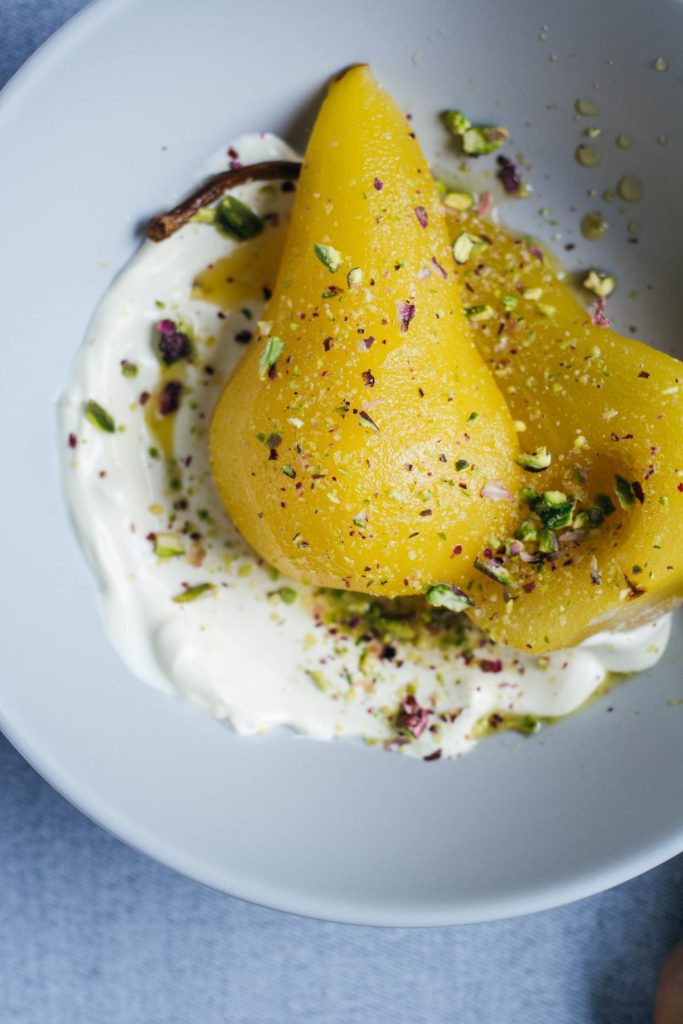 Poached Pears served with creme fraiche and pistachios in blue bowl