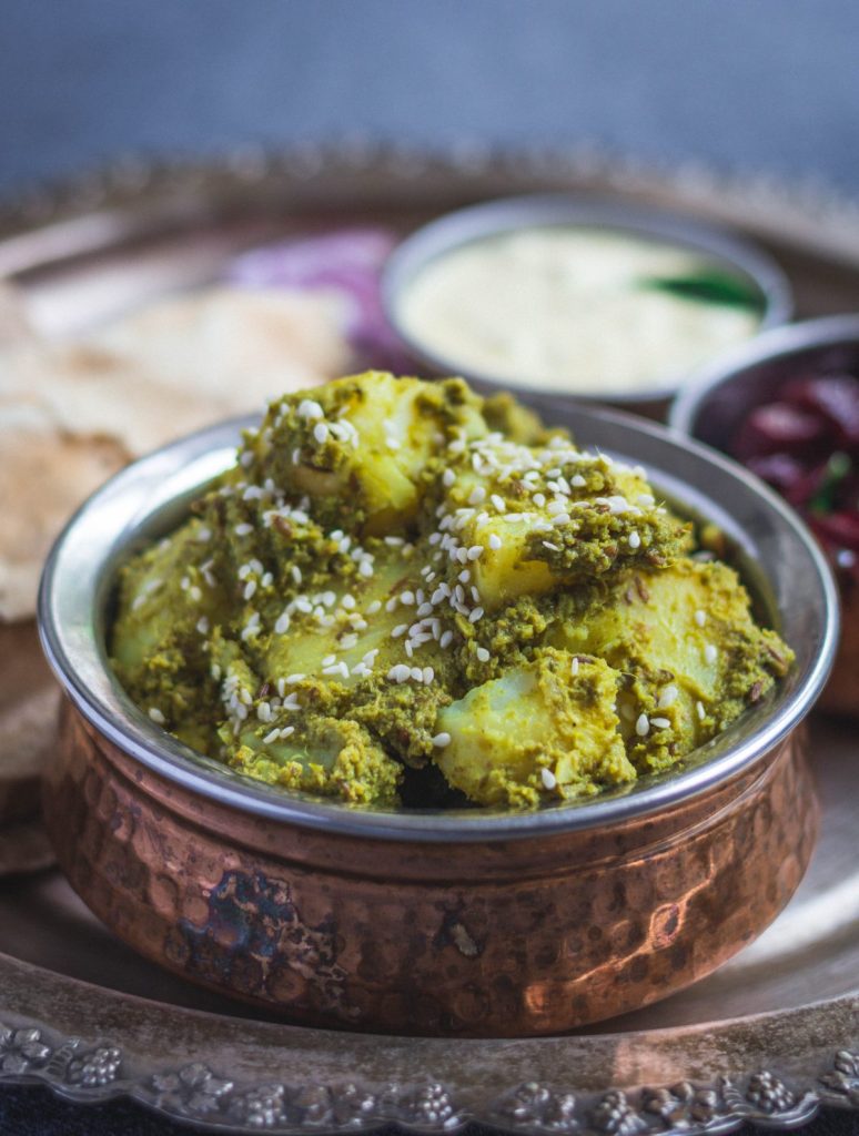 Potatoes in mint coriander masala served in copper bowl