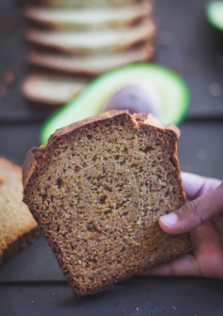 close up of hand holding a slice of avocado banana bread