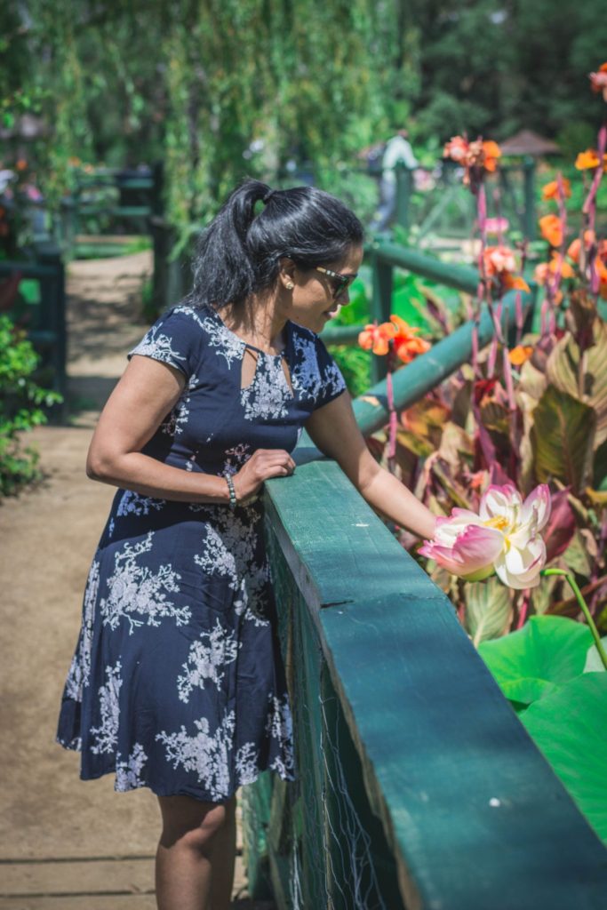 woman holding pink lotus near pond