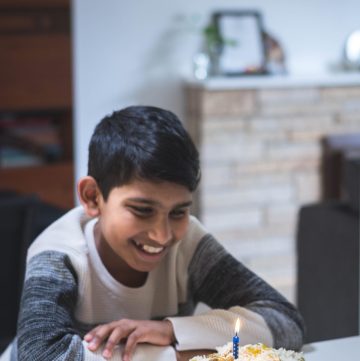 boy smiling at birthday candle on South Indian style mutton biryani on oval white platter