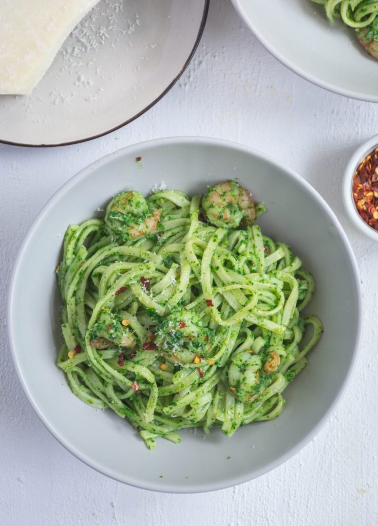 a bowl of pasta with pesto and prawns