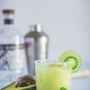 Spicy Avocado Margarita in glass garnished with lime and jalapeno slice