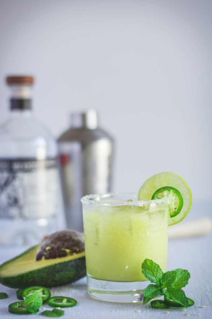 Spicy Avocado Margarita in glass garnished with lime and jalapeno slice