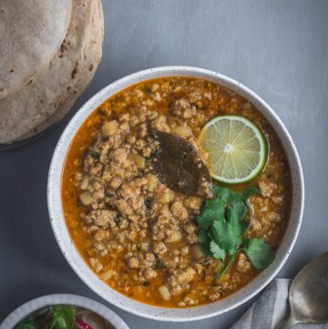 Indian pork mince curry garnished with lime and coriander leaves in grey bowl