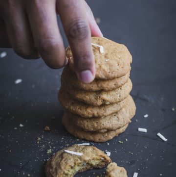 hand taking a coconut cookie from a stack of cookies