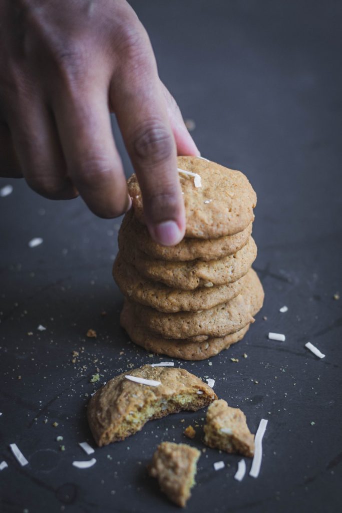 hand taking a coconut cookie from a stack of cookies