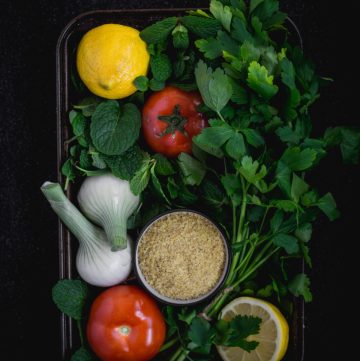 closeup of ingredients for tabbouleh in black tray