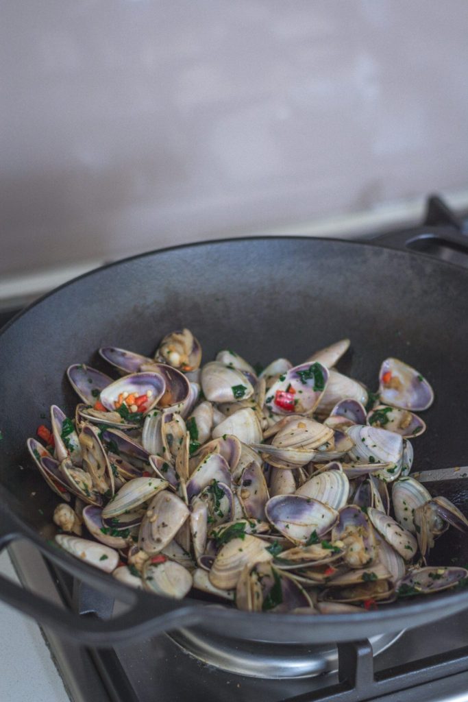 Cast iron wok with Taiwanese style pipis being cooked