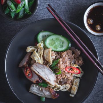 Thai style duck fried rice in black bowl with chopsticks on the side