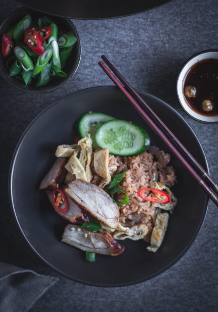 Thai style duck fried rice in black bowl with chopsticks on the side