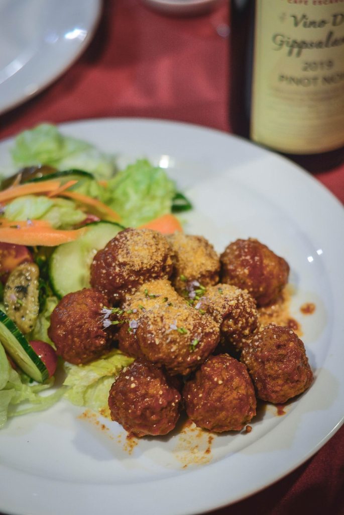 Spanish meatballs cooked in tomato sauce served with salad on white plate