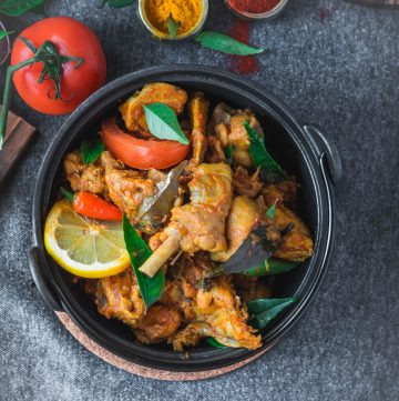 chicken dish with tomato and spices in black bowl