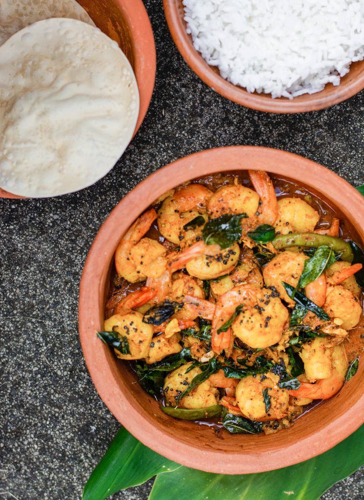 prawns in earthenware pot with rice and pappadums on the side