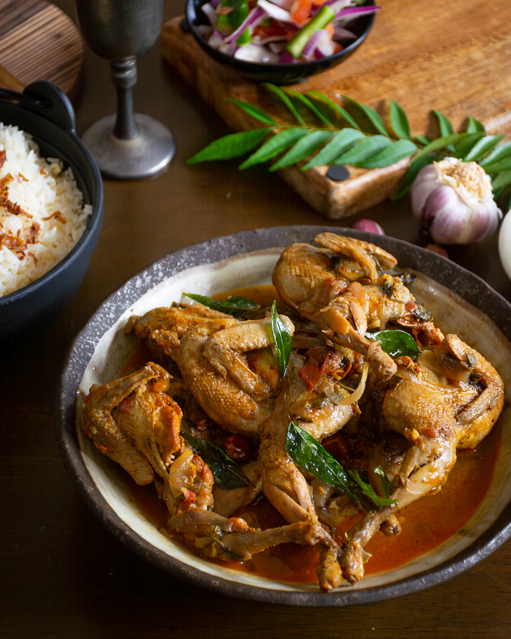 Quail curry served in grey bowl with rice on the side