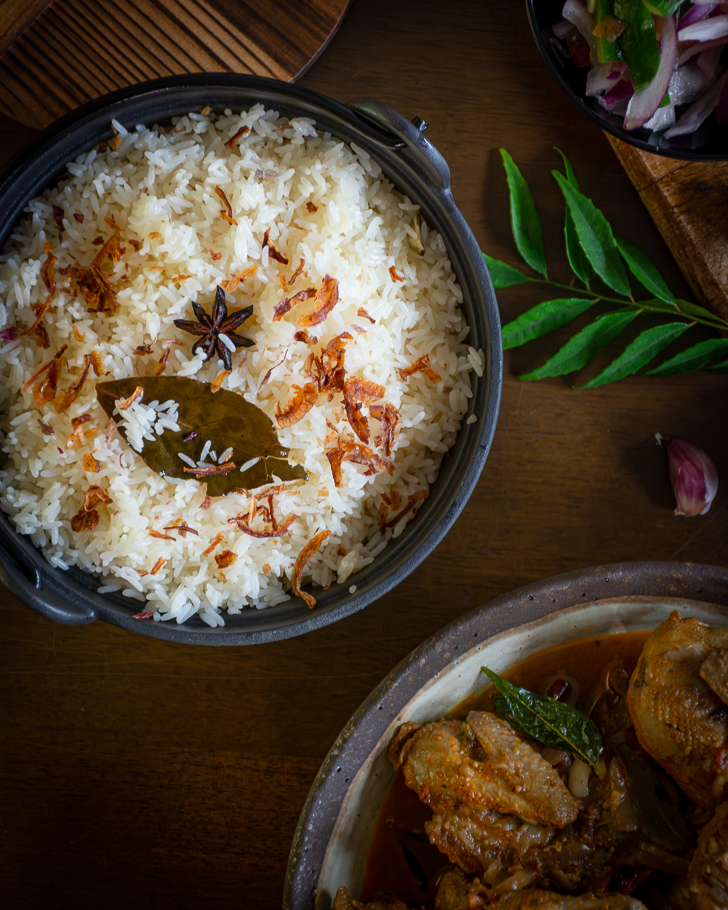 Rice dish garnished with fried shallots served in black bowl