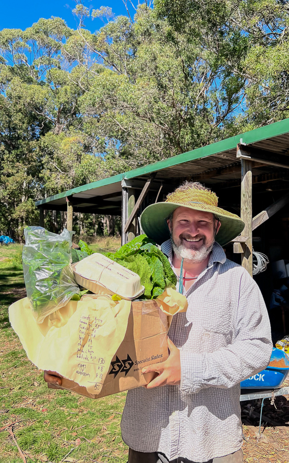 A man carrying a box filled with fresh vegetables